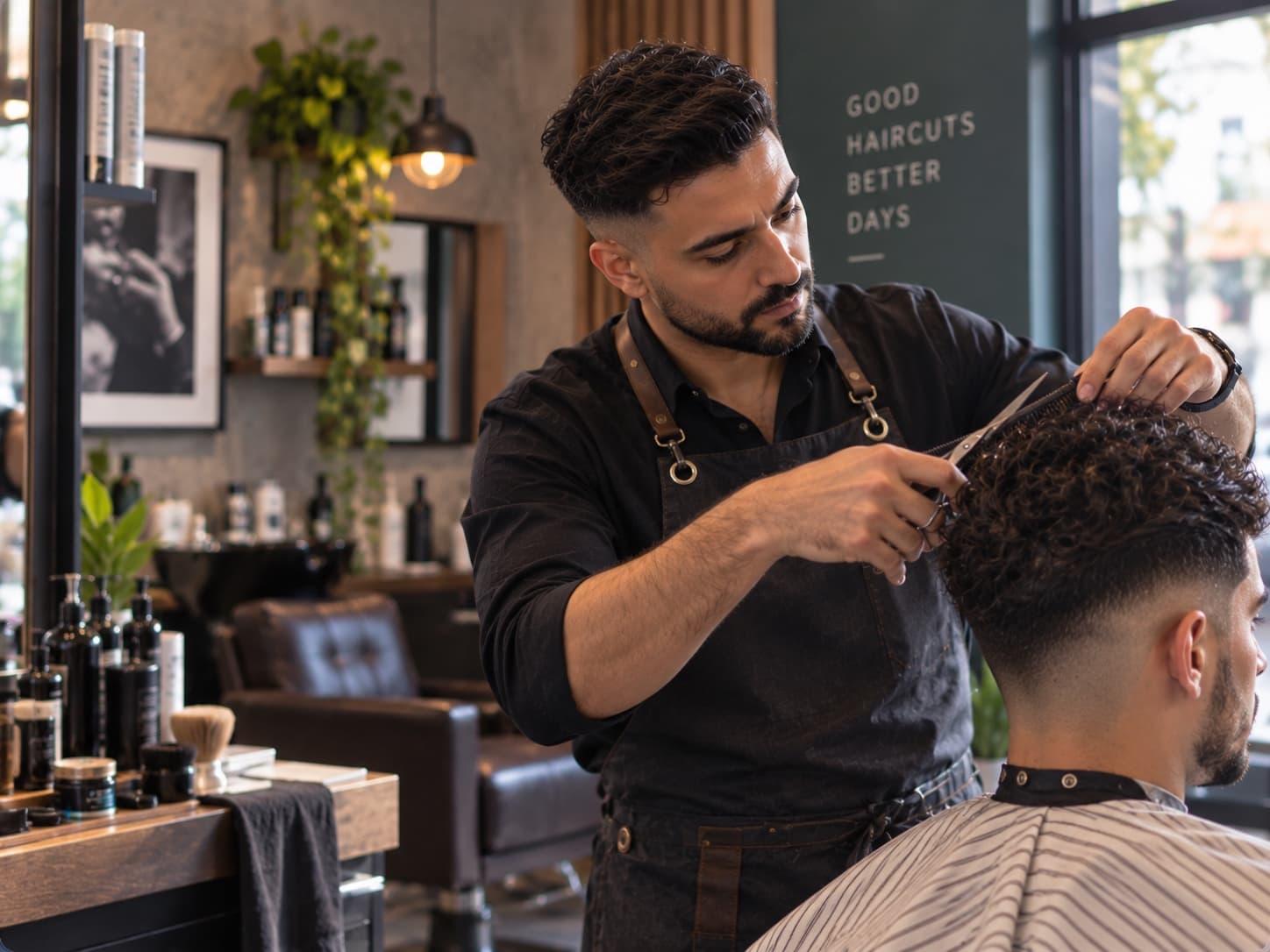 A barber cutting a client's curly hair with scissors in a modern barbershop